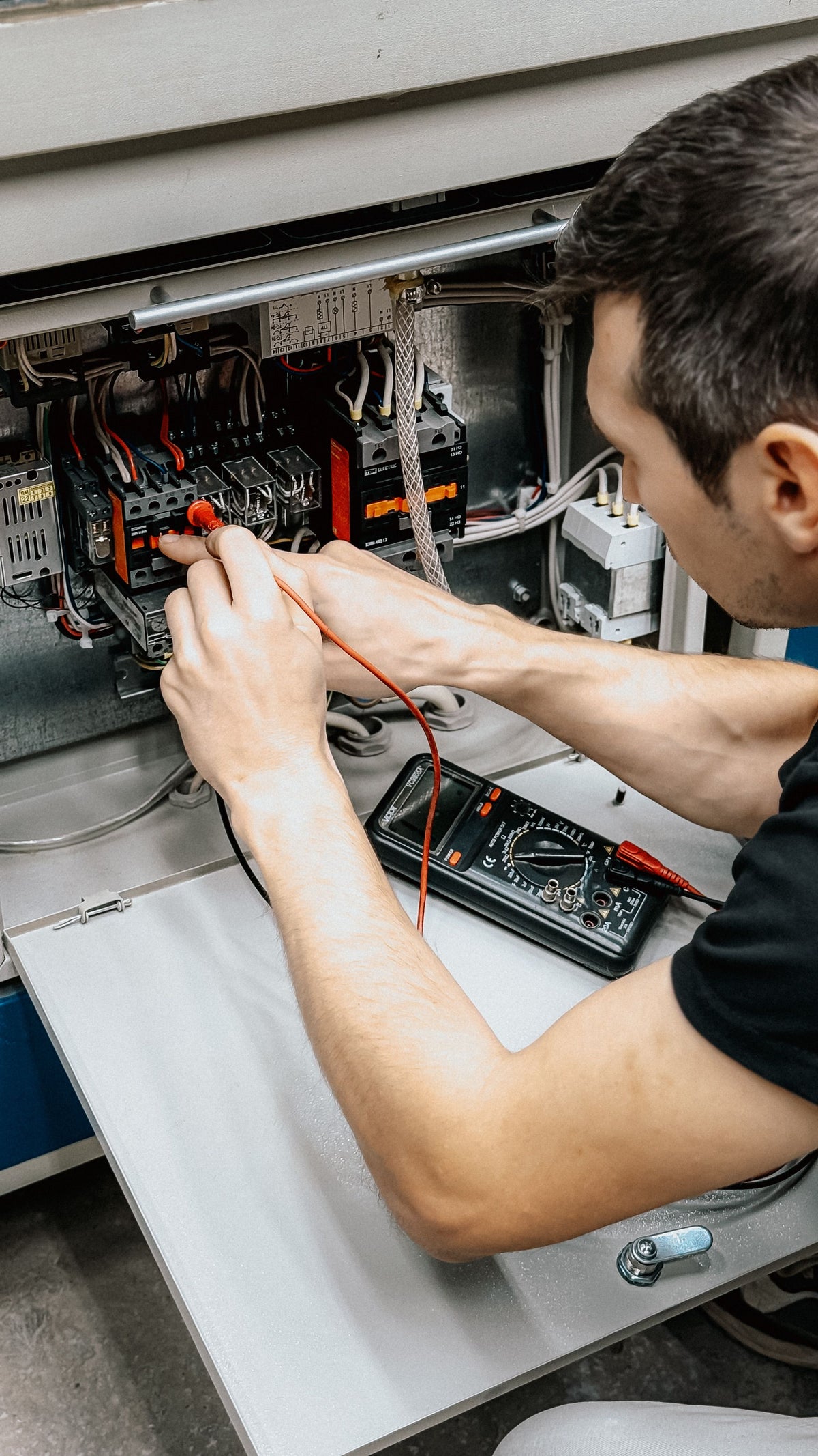 Elektriker prüft professionell einen Schaltschrank mit Multimeter